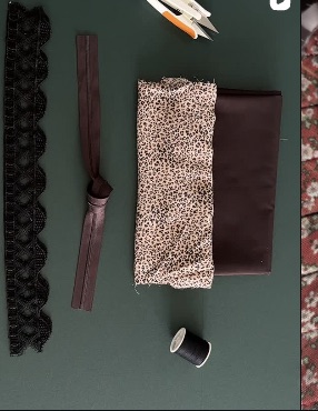 Fabric pieces, thread, and trim arranged on a craft table